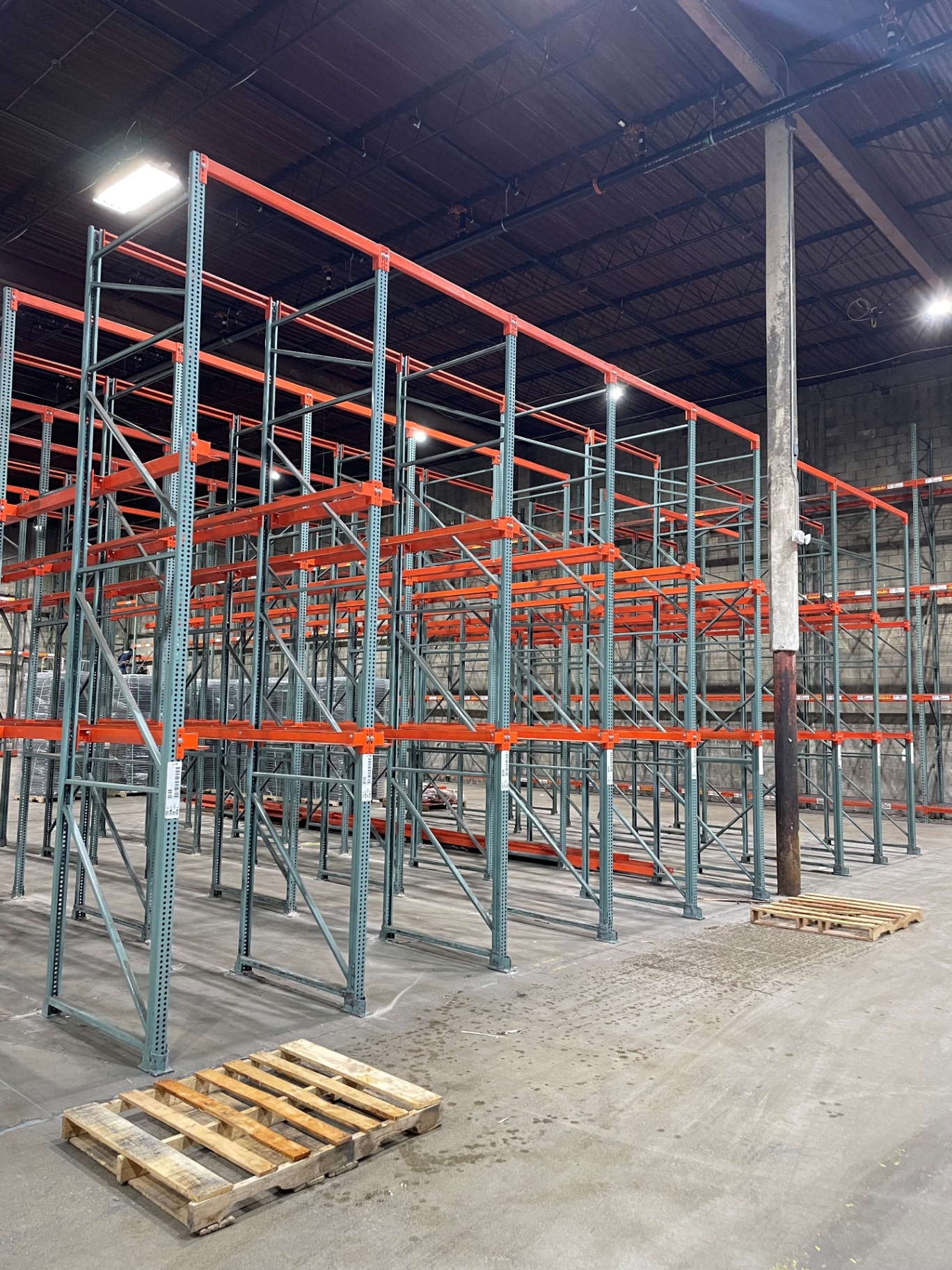 Drive-in pallet racking with grey uprights, orange rails, and deep storage bays